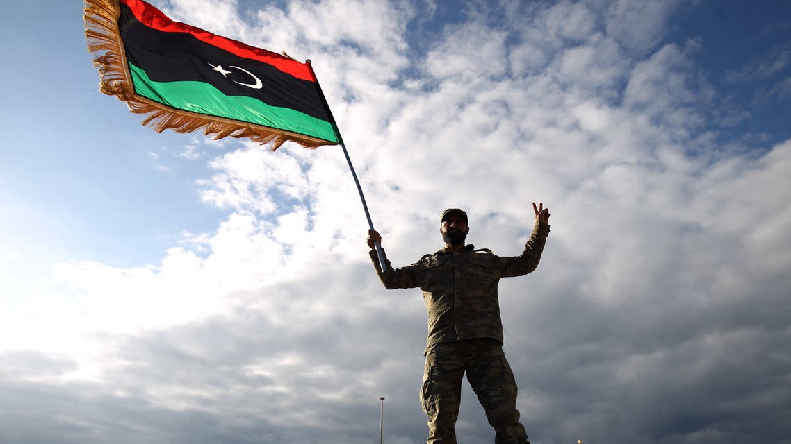 A Libyan soldier waves the national flag during a gathering to mark the eighth anniversary of the uprising in Libya's second city of Benghazi, on February 17, 2019. Eight years after the revolt in Libya against Moamer Kadhafi's authoritarian regime, a modern and democratic state remains a distant dream in a country which has been sliding from crisis to crisis.
