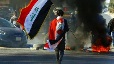 A demonstrator carries an Iraqi flag as he walks near burning tires, during ongoing anti-government protests in Najaf, Iraq January 12, 2020. (Photo: Reuters)