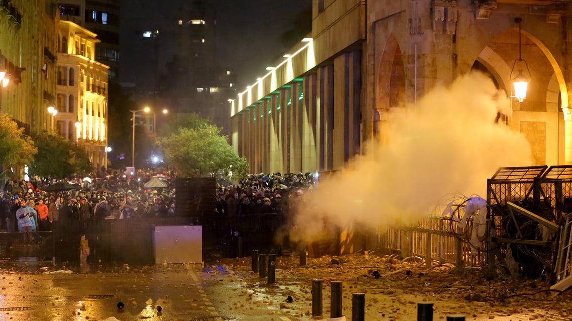 Lebanese protesters take cover behind a barricade amid clashes with riot police guarding a road leading to parliament in central Beirut on January 19, 2020. (AFP)