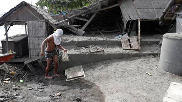 A fisherman stands beside a damaged house at a village near Taal volcano where residents have evacuated to safer grounds in Agoncillo, Batangas province. (AP)