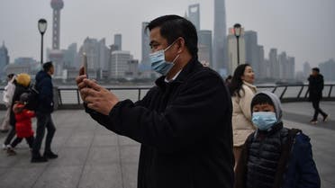 A man wearing a protective mask takes pictures on the promenade of the Bund along the Huangpu River in Shanghai on January 21, 2020. (Photo: Reuters)