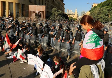 A girl has the national flag draped over her shoulders as riot police stand guard, during the ongoing anti-government protest, in Beirut, Lebanon, November 19, 2019. (Reuters)