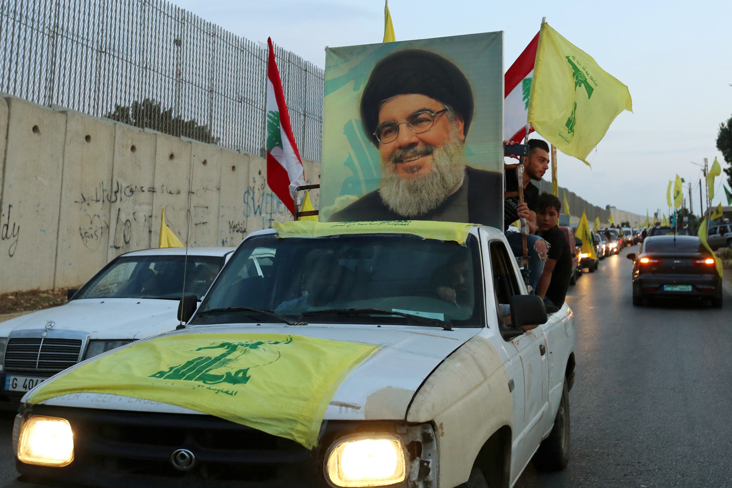 Supporters of Lebanon's Hezbollah leader Sayyed Hassan Nasrallah ride in a vehicle decorated with Hezbollah and Lebanese flags and a picture of him, as part of a convoy in Lebanon. (Reuters)