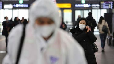 A woman wears a mask as an employee works to prevent a new coronavirus at Suseo Station in Seoul, South Korea. (AP)