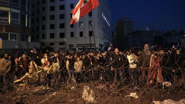 Lebanese anti-government demonstrators rally by barbed wire set by security forces to block a road leading to the government headquarters at the Grand Serail, in downtown Beirut, on January 25, 2020. (AFP)