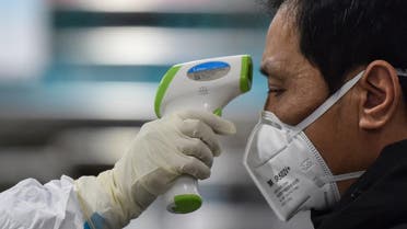 A medical staff member (L) wearing protective clothing to help stop the spread of a deadly virus which began in the city, takes the temperature of a man (R) at the Wuhan Red Cross Hospital. (AFP)