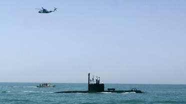 In this photo released by the semi-official Iranian Fars News Agency, a helicopter flies over a submarine during Iranian naval maneuvers in the Oman Sea in a part of Iranian southern waters (AP)