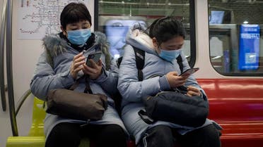 People wearing facemasks to help stop the spread of a deadly virus which began in Wuhan, use their phones on a train in Beijing on January 26, 2020. (AFP)