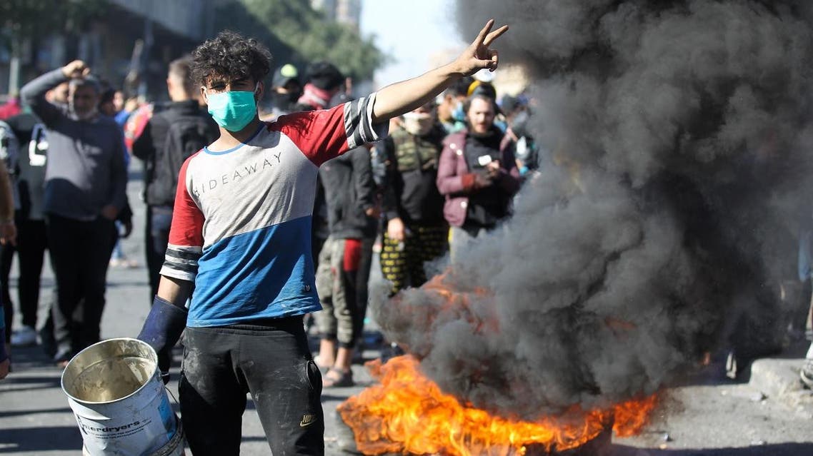 An Iraqi protester flashes the victory sign near burning tyres, during an anti-government rally in Al-Khillani square in the capital Baghdad, on January 27, 2020. (AFP)