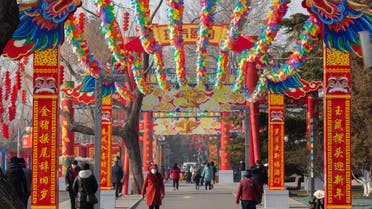 People wearing face masks walk under a canopy decorated with spinning colored fans for a canceled Lunar New Year temple fair at Longtan Park in Beijing. (AP)