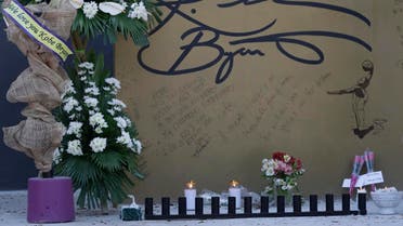 Flowers and candles are left on the wall with a signature of former NBA basketball player Kobe Bryant at the "House of Kobe" basketball court in Valenzuela, north of Manila, Philippines on Monday, Jan. 27, 2020. (AP)