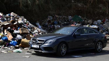 A man sits in his luxury car next to a garbage pile in a temporary dump in Beirut, Lebanon, on September 23, 2015. (File photo: AFP)