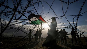 Palestinian protesters wave a national flag near concertina wire at the Israel-Gaza border, east of Rafah in the southern Gaza Strip. (AFP)