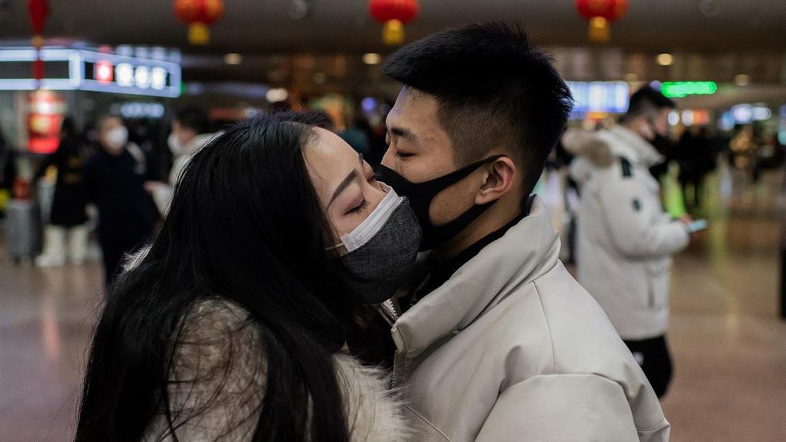 A couple, wearing protective masks, kisses goodbye as they travel for the Lunar New Year holidays, at Beijing West Railway Station in Beijing on January 24, 2020. (AFP)
