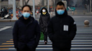 People wearing masks walk across a street as the country is hit by an outbreak of the new coronavirus, in Beijing, China January 28, 2020. REUTERS/Carlos Garcia Rawlins