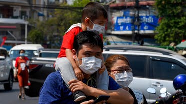 A family wear face masks as they walk along a street in Phnom Penh on January 29, 2020. (File photo: AFP)