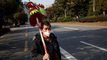 A man wearing a face mask carries the head of a dragon dance costume as he walks in the middle of an empty street in Changsha, Hunan province, China. (Photo: Reuters)