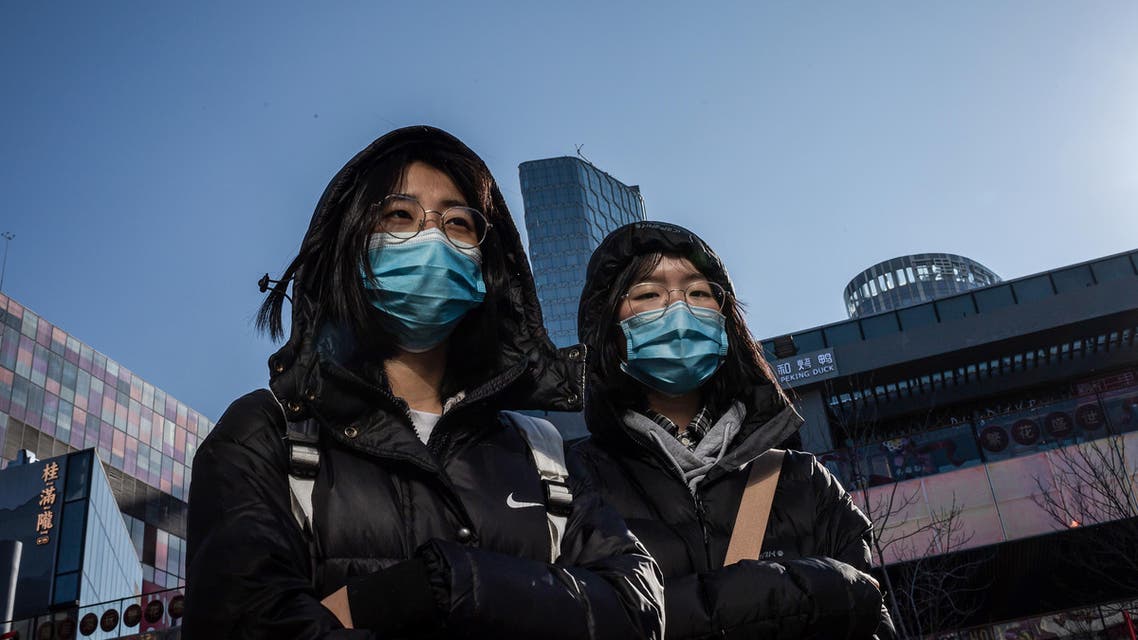 People wear protective masks as they walk outside a shopping mall in Beijing on January 23, 2020. China is halting public transport and closing highway toll stations in two more cities in Hubei province, the epicentre of a deadly virus outbreak, authorities said on January 23. NICOLAS ASFOURI / AFP