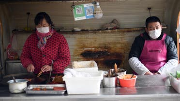 Workers wearing protective facemasks prepare food at a street stall in Beijing on January 26, 2020. (Photo: AFP)