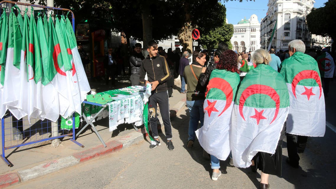ALGERIA-PROTESTS/RTS2ZQ4A24 Jan. 2020Algiers, AlgeriaDemonstrators wearing national flags walk past a street vendor during a protest demanding a change of the power structure in Algiers, Algeria January 24, 2020. (Reuters)