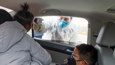 A medical worker in protective suit checks the body temperature of a car passenger at a checkpoint outside the city of Yueyang. (Reuters)