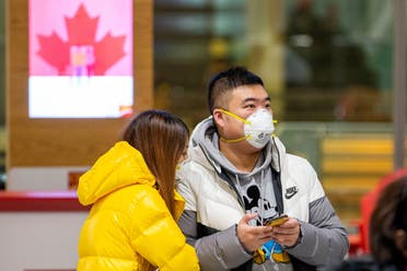 People waiting for passengers wear masks at Pearson airport arrivals, shortly after Toronto Public Health received notification of Canada's first presumptive confirmed case of coronavirus, in Toronto (Reuters)