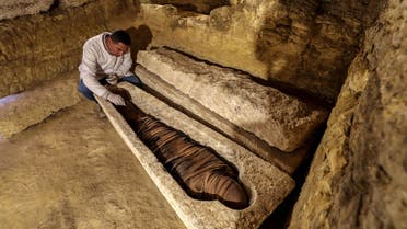 An Egyptian archeologist inspects a mummy in a limestone sarcophagus discovered along many finds in 3000-year-old communal tombs dedicated to high priests (AFP)