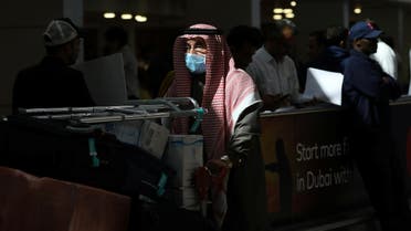 A traveller wears a mask as he pushes a cart with luggage at the Dubai International Airport, after the UAE's Ministry of Health and Community Prevention confirmed the country's first case of coronavirus. (Reuters)