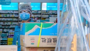 A clerk wearing a face mask and a plastic bag stands in a pharmacy in Wuhan in central China's Hubei Province. (AP)