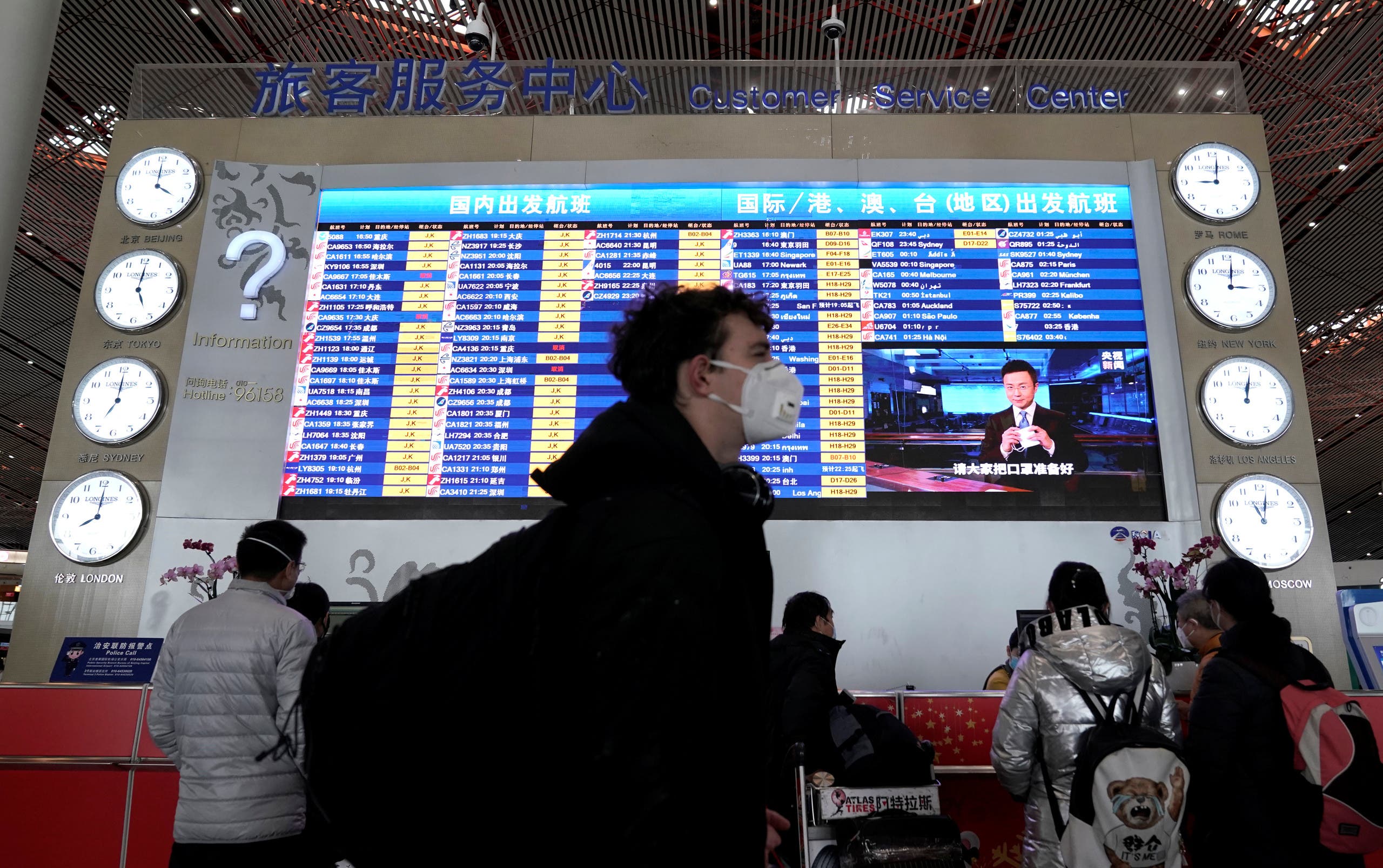 A foreign traveller wearing a mask walks past a departures information board at Beijing International Airport in Beijing, China as the country is hit by an outbreak of the new coronavirus, February 1, 2020. (Reuters)
