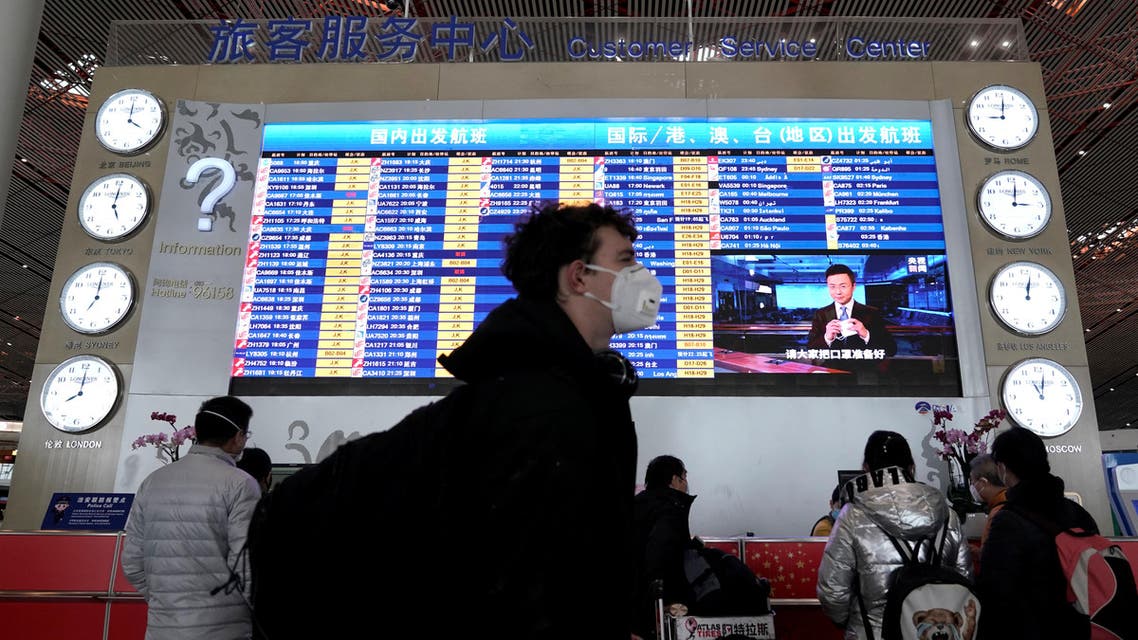 A foreign traveller wearing a mask walks past a departures information board at Beijing International Airport in Beijing, China as the country is hit by an outbreak of the new coronavirus, February 1, 2020. REUTERS
