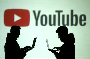 Silhouettes of mobile device users are seen next to a screen projection of YouTube logo in this picture illustration taken March 28, 2018. (Reuters)