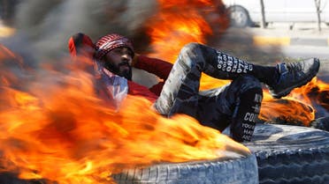 An Iraqi demonstrator sits amid burning tires blocking a road during ongoing anti-government protests in Najaf, Iraq February 2, 2020. (Photo: Reuters)