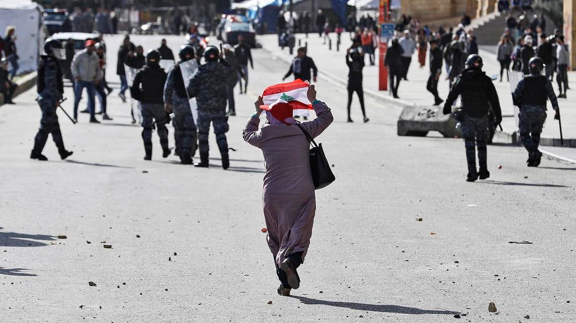 An elderly woman raises a Lebanese national flag behind riot police during clashes with anti-government protesters. (AFP)