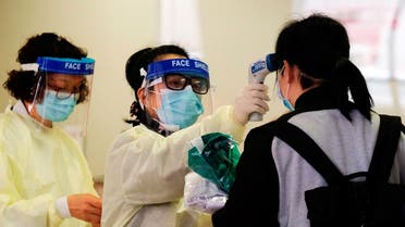 A medical worker takes the temperature of a woman in the reception of Queen Elizabeth Hospital, following the outbreak of a new coronavirus, in Hong Kong. (Reuters)