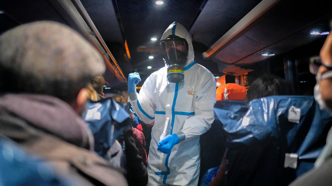 a military officer wearing a protective suit gives instructions to evacuees from Wuhan, China, as they travel to a hospital after their arrival at a military base in Wroclaw, Poland. (AP)