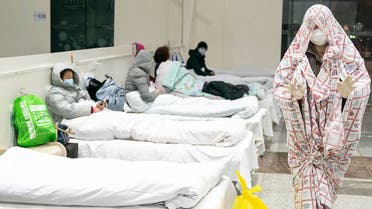 This photo taken on February 5, 2020 shows a patient (R) covered with a bed sheet at an exhibition centre converted into a hospital as it starts to accept patients displaying mild symptoms of the novel coronavirus in Wuhan in China's central Hubei province. China scrambled to find bed space for thousands of newly infected patients on February 6, as the toll from a deadly new virus jumped again with more than 28,000 people known infected nationwide and 563 deaths.