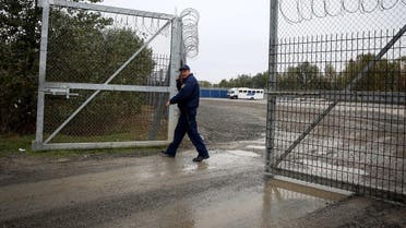 A member of hungarian police closes a razor wired fence at a migrant transit centre near Roszke, at the border crossing with Serbia on October 29, 2019. (AFP)