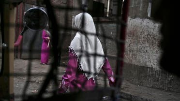 an Egyptian woman seen from a motorized rickshaw walks on a street, near the home of 13-year-old Sohair el-Batea who died undergoing the procedure of female genital mutilation committed by Dr. Raslan Fadl, in Dierb Biqtaris village, on th AP