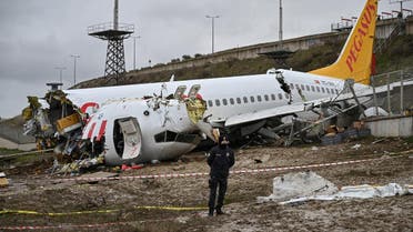 A Turkish police officer stands guard on site of a plane accident and in front of the wreckage of Pegasus Airlines Boeing 737 airplane that skidded off the runway upon landing at the Sabiha Gokcen airport, in Istanbul, on February 6, 2020. (AFP)