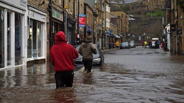 People wade through floodwater in the streets of Hebden Bridge, northern England, on February 9, 2020, as Storm Ciara swept over the country. (AFP)