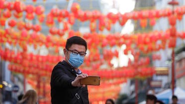 A man wears a mask as he takes a photograph in China Town in London, Friday, Feb. 7, 2020. (AP)
