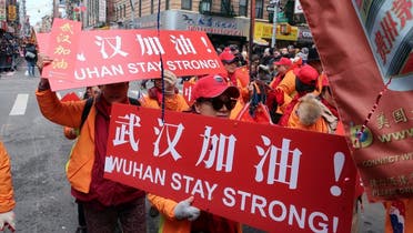 People carry signs in support of Wuhan, China, at the center of the coronavirus outbreak, during the Lunar New Year parade, on February