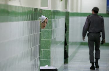 An Iranian inmate peers from behind a wall as a guard walks by at the female section of the infamous Evin jail, north of Tehran, on June 13, 2006. (File photo: AFP)