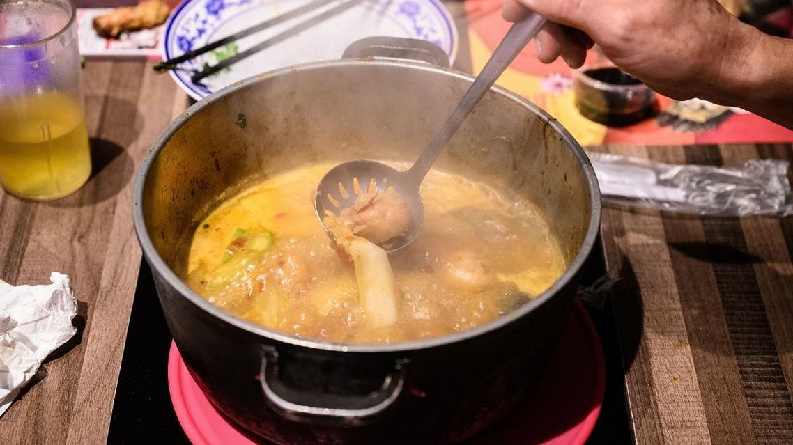 a customer spoons out some food as he eats with a group of friends at 66 Hotpot, a family-run restaurant in the bustling district of Mongkok in Hong Kong. (AFP)