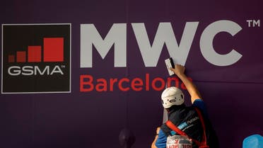 A worker fixes a poster announcing the Mobile World Congress 2020 in a conference venue in Barcelona, Spain. (AP)