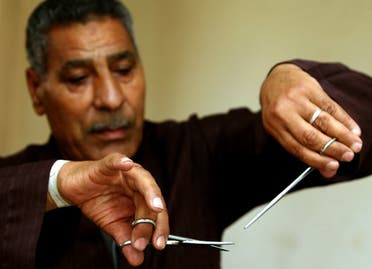 Hassan Hafez, a barber, mimics the way he used to perform female genital mutilation (FGM) in Minia June 13, 2006. (Reuters)