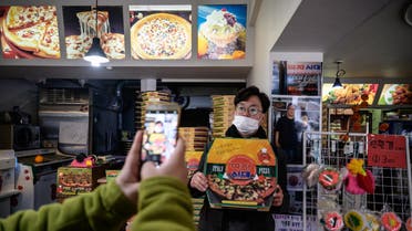 A customer poses before a photo of film director Bong Joon-ho at the 'Sky Pizza' restaurant in Seoul on February 13, 2020. (AFP)