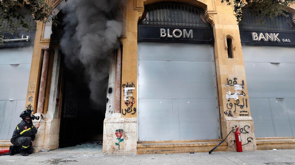A firefighter looks before entering a bank that was set on fire by anti-government protesters, during a protest in downtown Beirut, Lebanon. (AP)