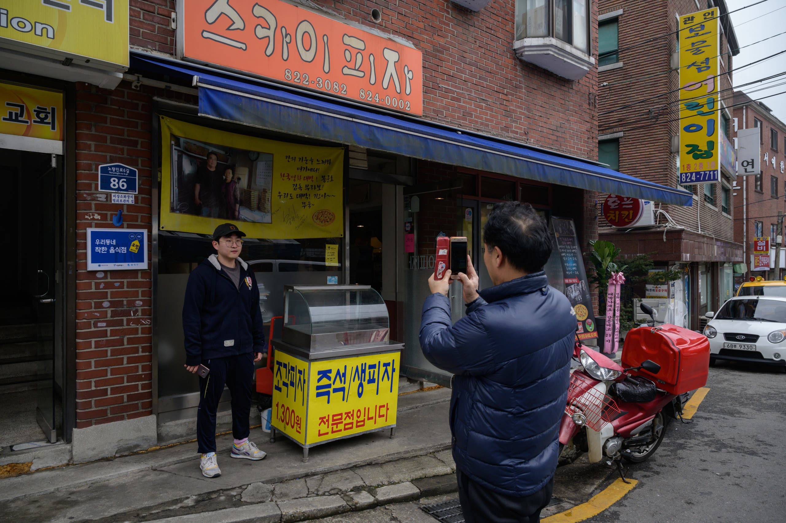 A customer poses before a photo of film director Bong Joon-ho at the 'Sky Pizza' restaurant in Seoul on February 13, 2020. (AFP)